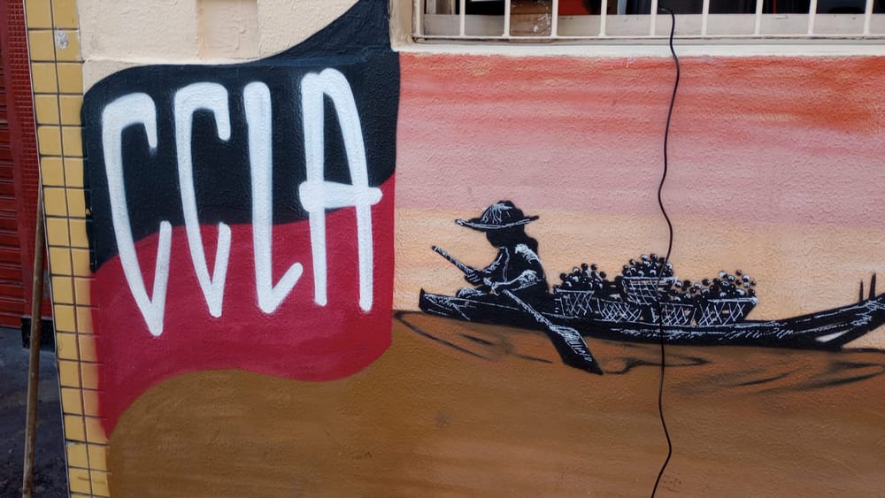 Entrée du CCLA avec un drapeau rouge et noir et le dessin d'une embarcation indigène sur le mur